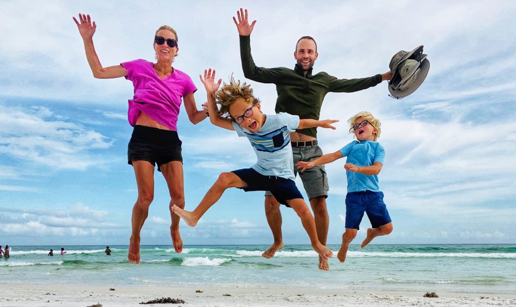 Family jumping on a white sand beach in Florida. 